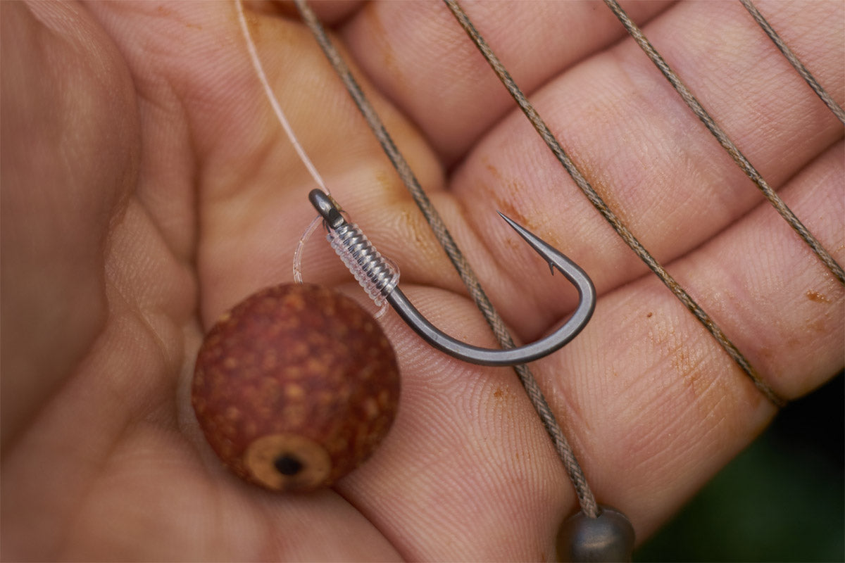A Chod rig section tied with Revolve stiff link a razor sharp Size 4 Duropoint Chod hook and an essential baits B5 popup plugged with Cork. In the background a Lead free leader makes up a helicopter setup.